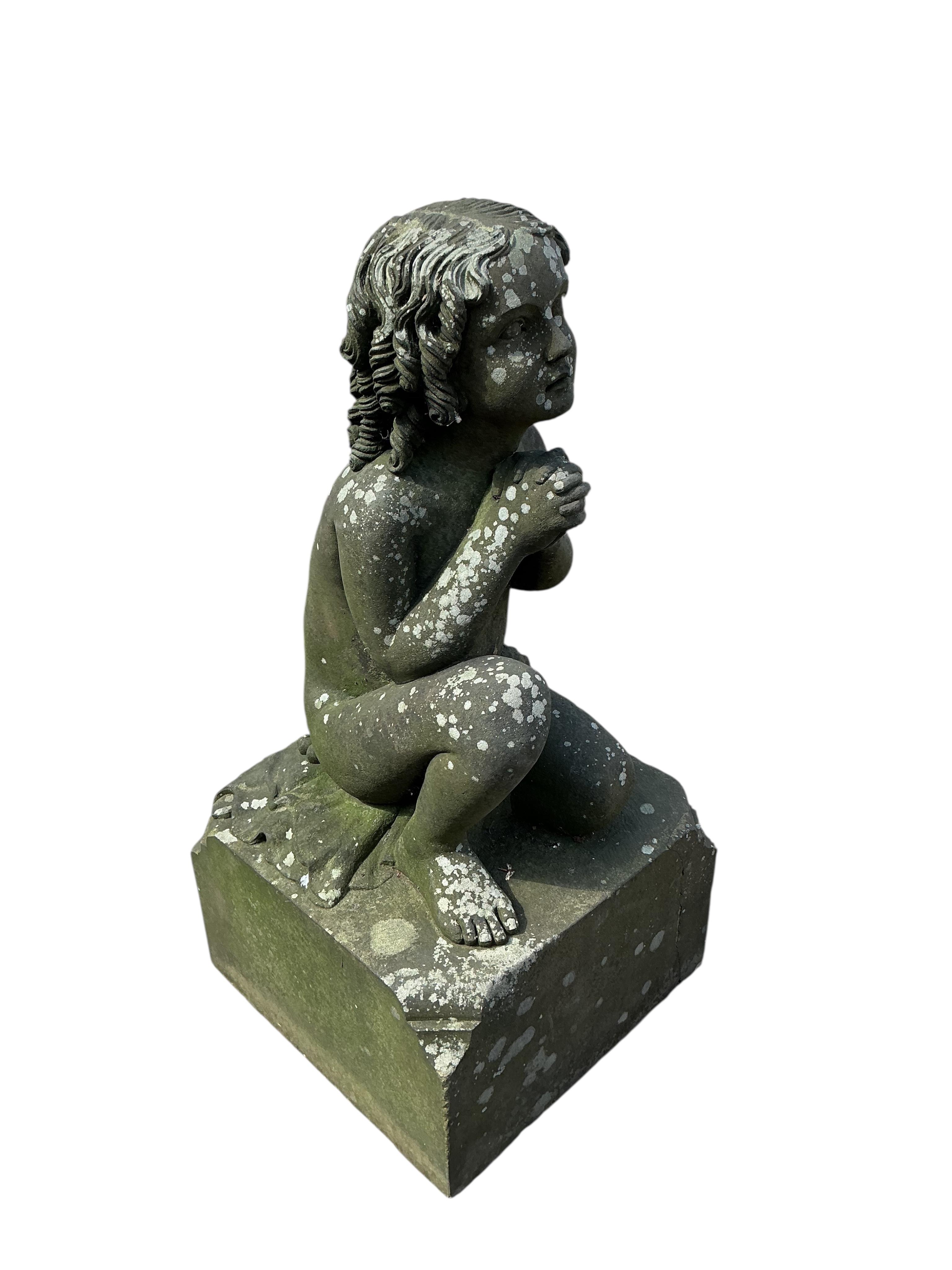 A stone garden ornament of a kneeling child at prayer, height 95cm